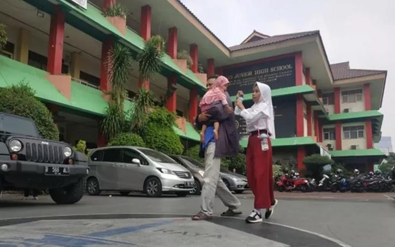 Orangtua siswa mengantarkan anaknya mendaftar sekolah di SMP 115, Jakarta, Senin (24/6/2019)./Antara