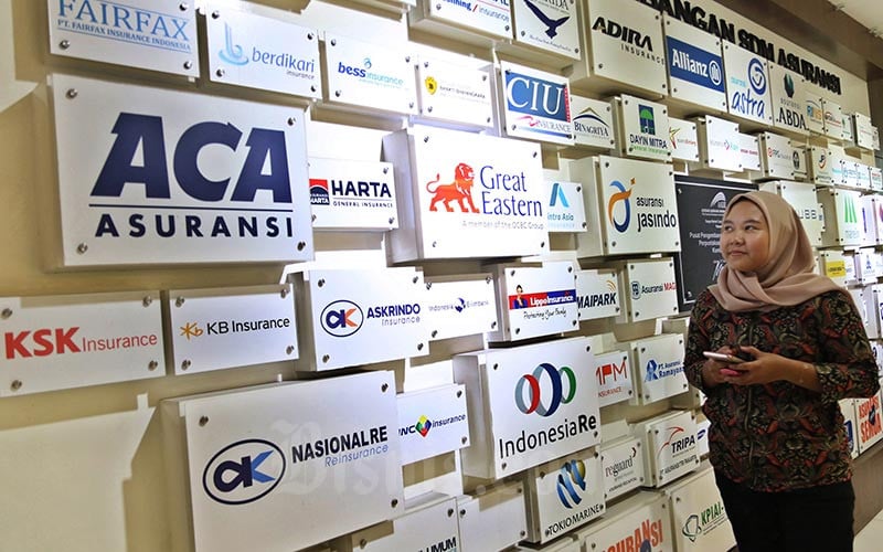 Karyawan melintasi logo-logo perusahaan asuransi di Kantor Asosiasi Asuransi Umum Indonesia (AAUI), Jakarta, Selasa (11/02/2020). Bisnis/Eusebio Chrysnamurti