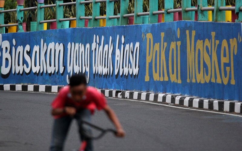 Pesepeda melintas di dekat dinding bermural di Surabaya, Jawa Timur, Minggu (18/10/2020). Mural di sepanjang dinding viaduk Gubeng itu sebagai sarana imbauan kepada masyarakat untuk menerapkan protokol kesehatan pencegahan penularan Covid-19./Antara-Didik Suhartono