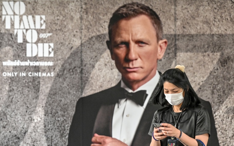 Warga melintas di depan poster film James Bond No Time to Die/Bloomberg