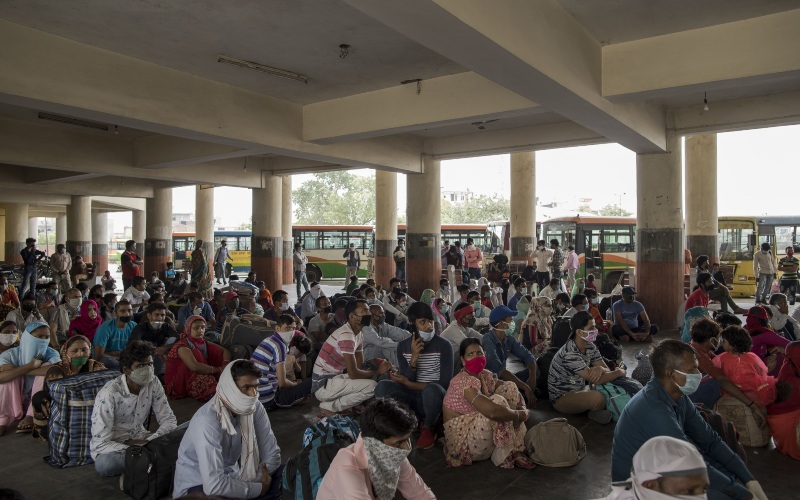 Pekerja migran menunggu di terminal bus untuk pulang ke kampung halaman masing-masing, di Greater Noida, Uttar Pradesh, India, Jumat (29/5/2020)./Bloomberg-Anindito Mukherjee