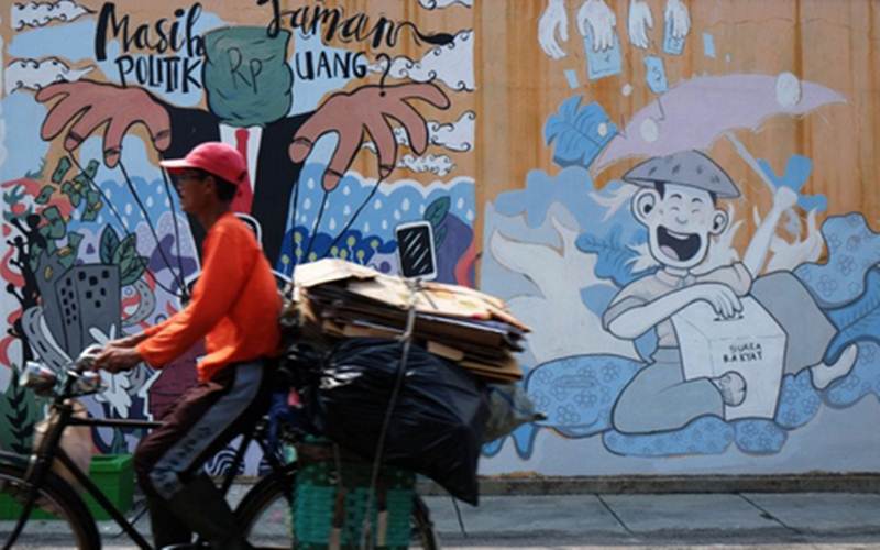 Ilustrasi - Seorang pesepeda melintas di depan mural ajakan menjauhi praktik politik uang./Antara-Maulana Surya 