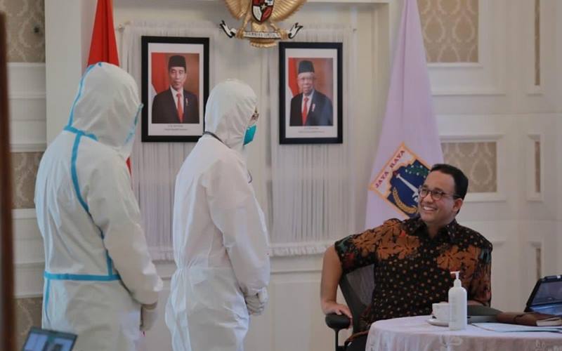 Gubernur DKI Jakarta Anies Baswedan dua dua tenaga kesehatan mengenakan alat pelindung diri (APD). Anies psoitif Covid-19 dan dalam masa isolasi mandiri. JIBI/Bisnis-Nancy Junita @kawalCOVID19