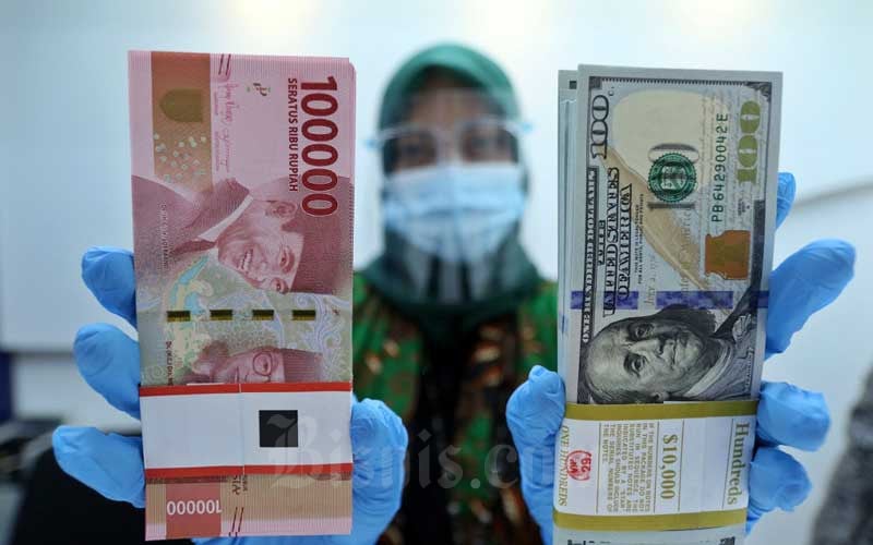 Karyawan menunjukan Rupiah dan Dolar AS di Jakarta, Rabu (27/1/2021). Nilai tukar rupiah di pasar spot ditutup menguat 15 poin atau 0,11 persen menjadi Rp14.050 per dolar AS. Bisnis/Eusebio Chrysnamurti