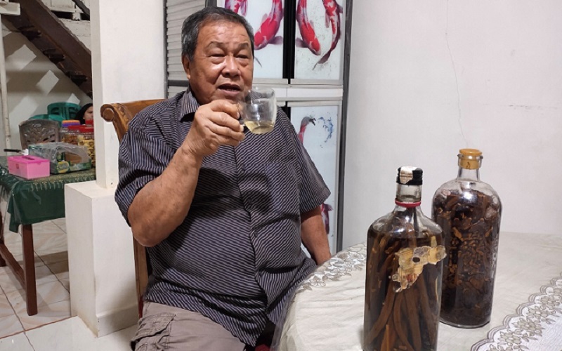 Petrus Mait, seorang warga masyarakat di Tomohon, Sulawesi Utara, sedang menikmati minuman keras tradisional cap tikus yang telah diracik dengan beberapa rempah tambahan untuk memperkuat cita rasanya, Sabtu (2/1/2021). - Bisnis/Emanuel B. Caesario.