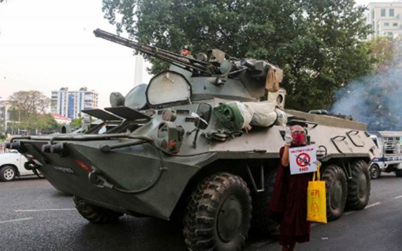 Seorang biksu Buddha memegang tanda berdiri di samping kendaraan lapis baja saat protes terhadap kudeta militer, di Yangon, Myanmar, Minggu (14/2/2021)./Antara/Reuters-Stringer