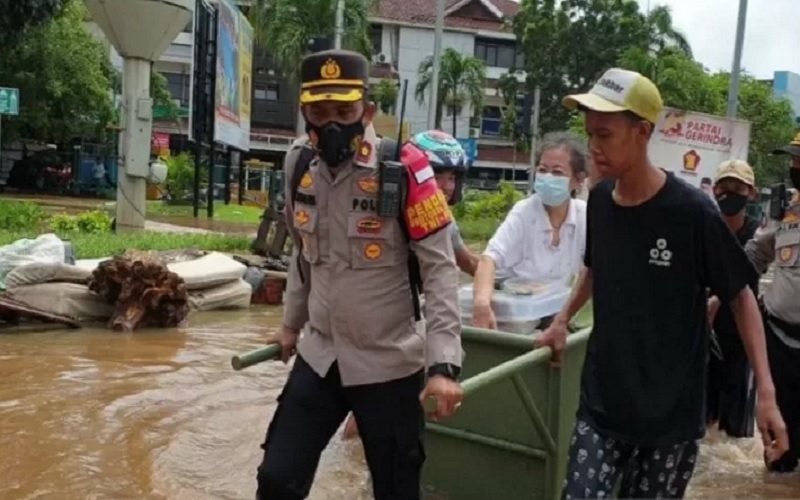 Kapolsek Kembangan Jakarta Barat Kompol Khoiri menarik gerobak yang dinaiki Aisyah (65) untuk menerjang banjir di Jalan Puri Kembangan, Jakarta Barat, Sabtu (20/2/2021)./Antararnrn