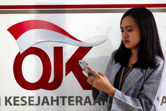 Karyawan melintas di dekat logo Otoritas Jasa Keuangan (OJK) di Jakarta. /Bisnis-Abdullah Azzam