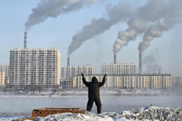 Polusi China: Seorang pria melakukan olahraga pagi dengan latar belakang asap pabrik di seberang sungai Songhua di Provinsi Jilin, China (24/2/2013)./Reuters-Stringer