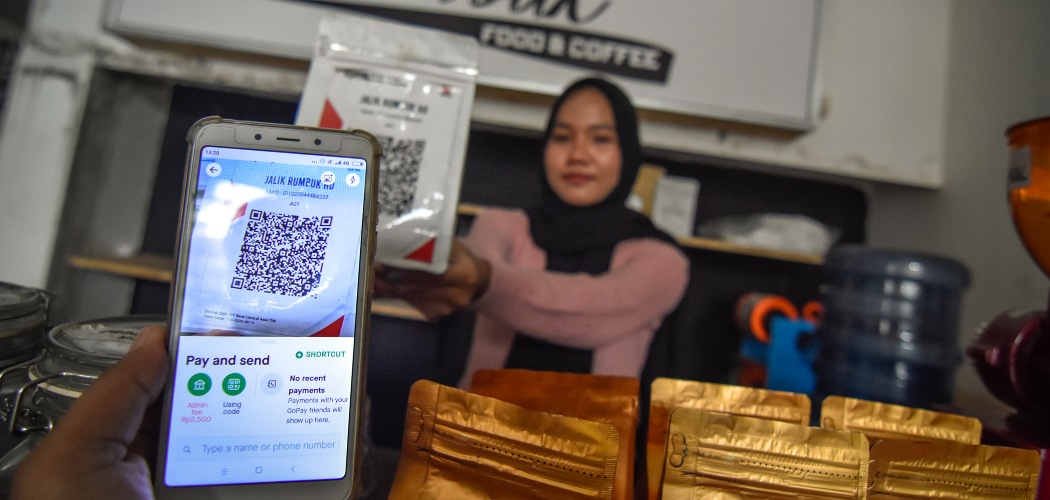 Seorang warga menggunakan pembayaran nontunai Quick Response Indonesia Standard (QRIS) saat membeli kopi di warung kopi Jalik Rumbuk di Mataram, NTB, Selasa (12/1/2021)./ANTARA FOTO-Ahmad Subaidi