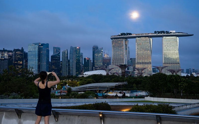 Seseorang mengambil gambar Marina Bay Sands Hotel & Casino Singapura./Bloomberg/SeongJoon Cho