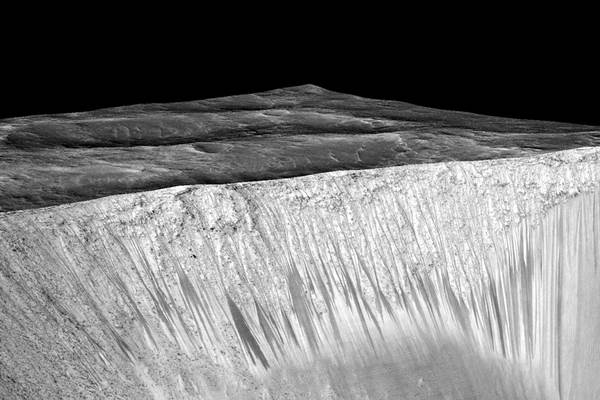 Gambar NASA yang menunjukkan lintasan gelap dan sempit sepanjang 100 meter yang disebut lereng lineae mengalir menuruni bukit di Mars diduga terbentuk oleh aliran air saat ini./Reuters