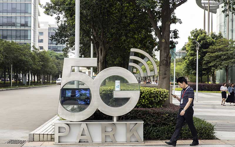 Warga menggunakan smartphone berjalan melewati papan Taman 5G di markas Huawei Technologies Co. di Shenzhen, China, Rabu(22/5/2020).Bloomberg/Qilai Shen