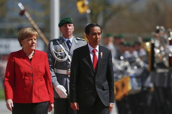 Presiden Joko Widodo (kanan) dan Kanselir Jerman Angela Merkel memeriksa pasukan, saat upacara penyambutan kedatangan Jokowi di Berlin, Jerman, Senin (18/4)./REUTERS-Hannibal Hanschke