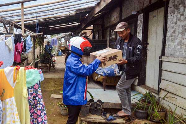 Kurir JNE memberikan paket kepada warga yang tinggal di Desa Cipanjalu, Palintang, Kabupaten Bandung, Jawa Barat, Kamis (3/1/2019)./ANTARA-Raisan Al Farisi