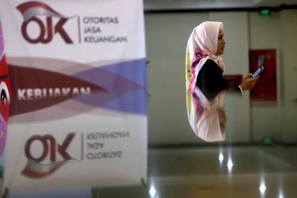 Karyawan melintas di dekat logo Otoritas Jasa Keuangan (OJK) di Jakarta, Rabu (3/10/2018)./JIBI-Nurul Hidayat