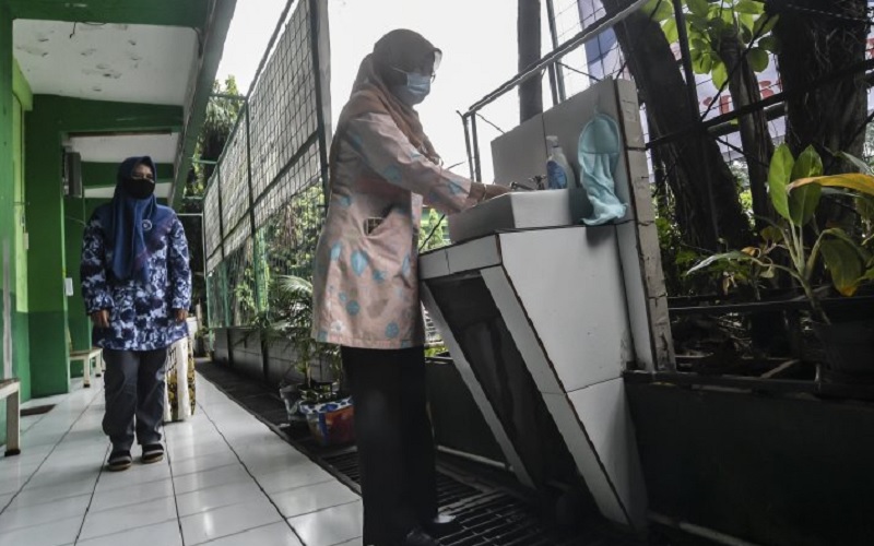 Orangtua murid mencuci tangan sebelum masuk ke dalam kelas saat mengikuti simulasi sekolah campuran tatap muka dan daring (hybrid) di SMP 255, Jakarta Timur, Selasa (30/3/2021)./Antara