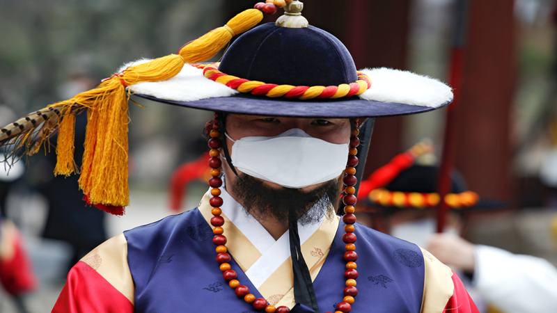 Seorang pekerja berkostum tradisional Korea mengenakan topeng pelindung untuk mencegah tertularnya virus corona selama pemeragaan ulang Royal Guards Changing Ceremony di depan Istana Deoksu di Seoul, Korea Selatan, 31 Januari 2020./Reuters
