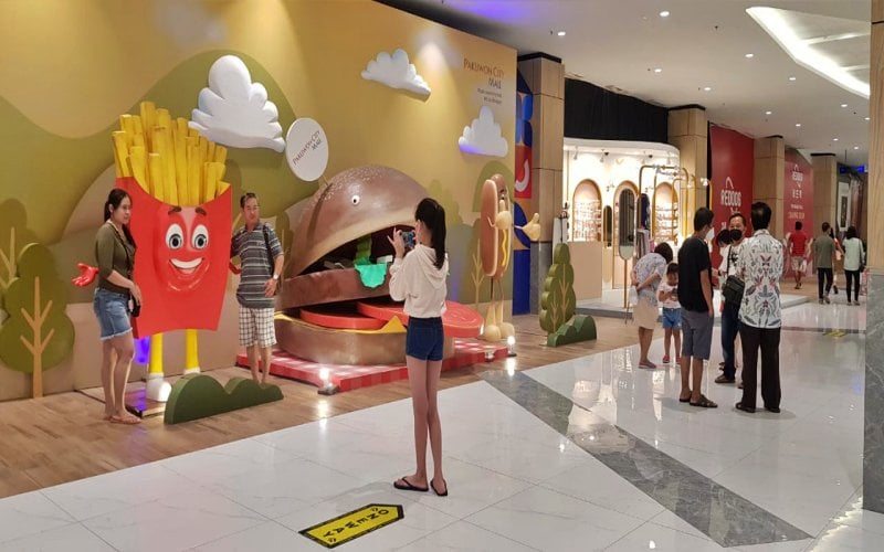 Pengunjung Pakuwon City Mall Surabaya tengah berfoto dengan salah satu ikon kuliner saat Hari Raya Idulfitri, Kamis (13/5/2021)/Bisnis-Peni Widarti
