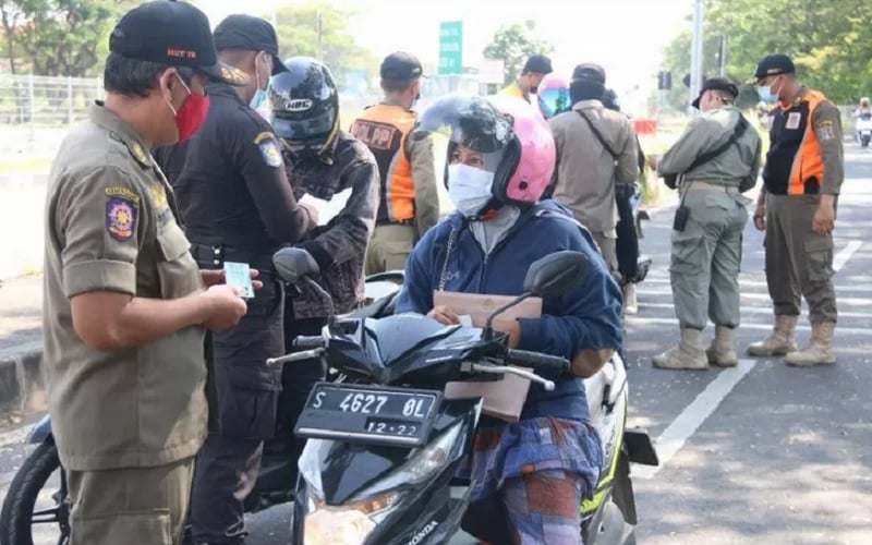 Sejumlah petugas melakukan pemeriksaan kepada warga yang hendak ke Kota Surabaya melalui Jembatan Suramadu, Selasa (15/6/2021)./Antararn