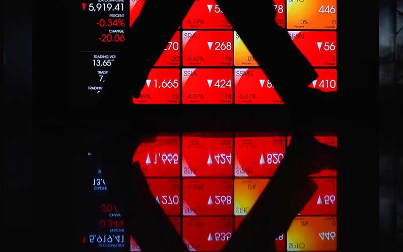 Karyawan melintas di dekat layar pergerakan indeks harga saham gabungan (IHSG) di Bursa Efek Indonesia, Jakarta, Selasa (29/6/2021). Bisnis/Fanny Kusumawardhani