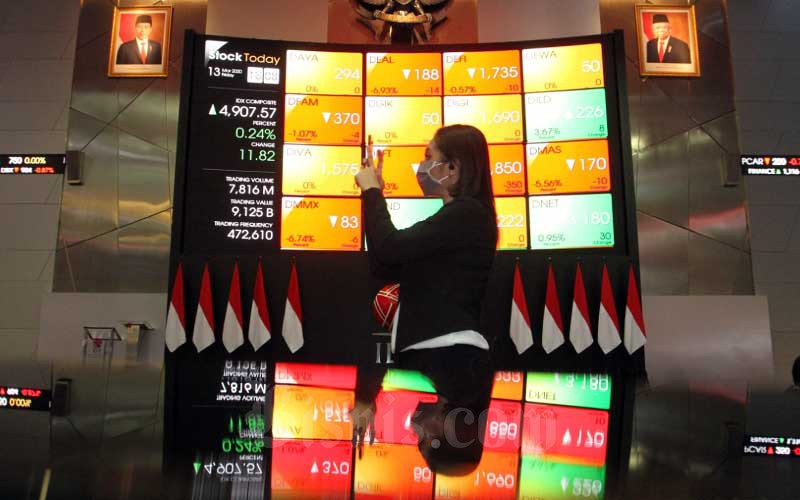 Pengunjung berada didekat papan elektronik yang menampilkan perdagangan harga saham di lantai Bursa Efek Indonesia di Jakarta, Jumat (13/3/2020). Bisnis/Dedi Gunawan