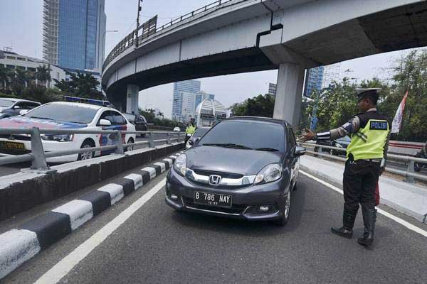 Petugas Ditlantas Polda Metro Jaya memberhentikan mobil berpelat nomor genap yang memasuki Jalan Gatot Soebroto, Jakarta, Rabu (1/8/2018)./ANTARA-Hafidz Mubarak A