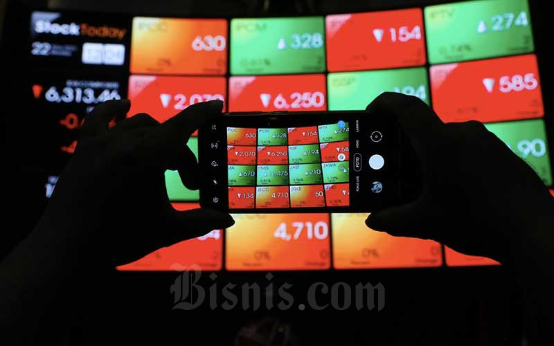 Pengunjung memotret papan elektronik yang menampilkan pergerakan indeks harga saham gabungan (IHSG) di Bursa Efek Indonesia, Jakarta, Senin (22/3/2021). Bisnis/Eusebio Chrysnamurti