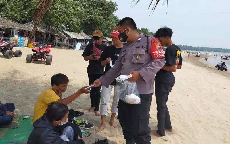 Polisi membagikan masker kepada para pengunjung atau wisatawan di Pantai Anyer di Serang, Minggu (12/9/2021)./Antara-Mulyana