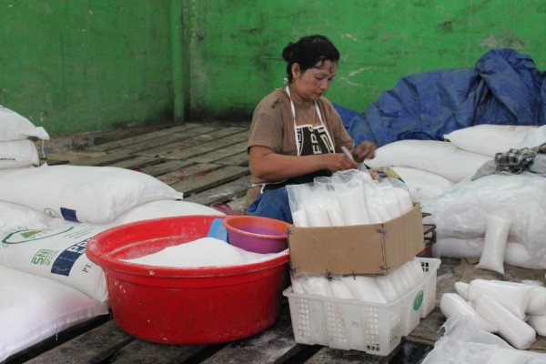 Salah satu pedagang gula dipasar tradisional sedang mengemasi gula pasir untuk dijual kembali / Arief Rahman
