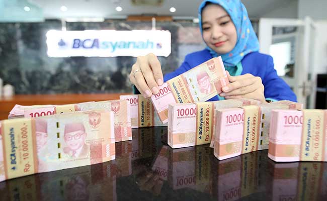 Karyawan menata uang Rupiah di cabang Bank BCA Syariah di Jakarta. Bisnis/Abdullah Azzam