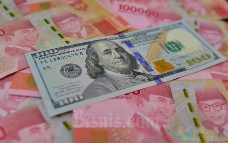Petugas menunjukkan mata uang dolar AS dan rupiah di Money Changer, Jakarta, Senin (19/4/2021). Bisnis/Fanny Kusumawardhani
