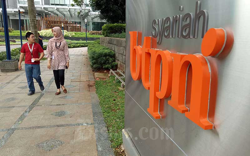 Pejalan kaki berjalan melewati logo PT Bank Tabungan Pensiunan Nasional Syariah Tbk atau BTPN Syariah di Jakarta, Senin (13/1/2020). Bisnis/Dedi Gunawan