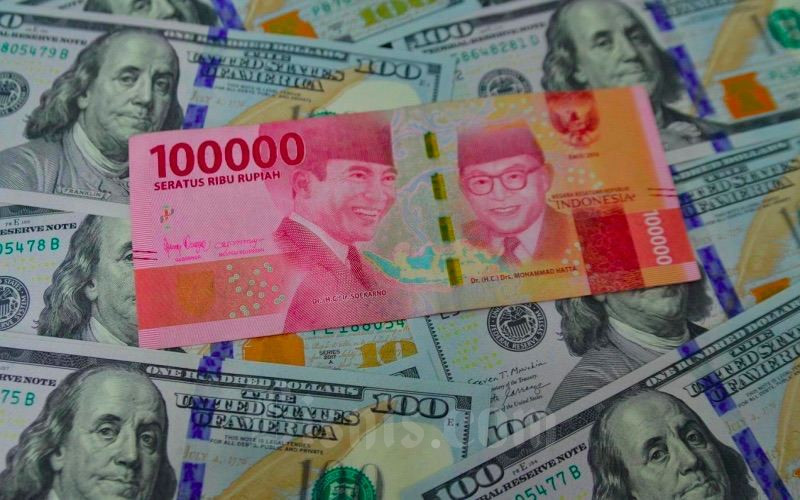 Petugas menunjukkan mata uang dolar AS dan rupiah di Money Changer, Jakarta, Senin (19/4/2021). Bisnis/Fanny Kusumawardhani