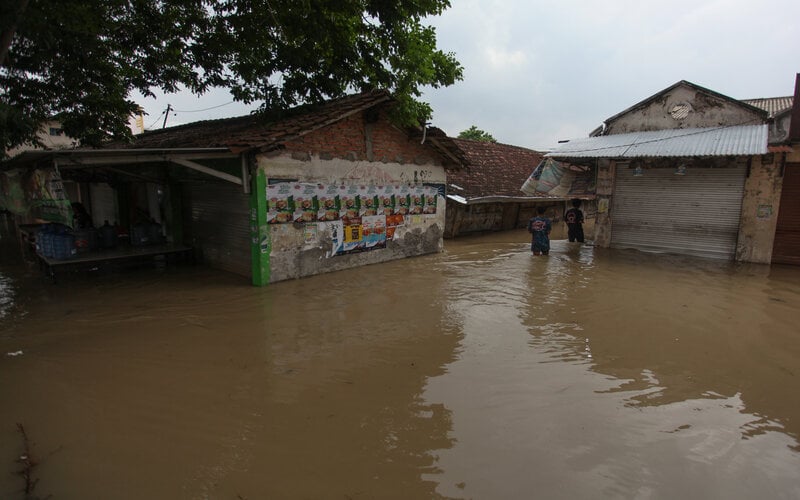 Warga berusaha menerobos banjir di Pasar Benjeng, Gresik, Jawa Timur, Jumat (5/11/2021). Banjir tersebut disebabkan meluapnya air Sungai Kali Lamong yang mengakibatkan sejumlah desa di Kecamatan Balongpanggang dan Kecamatan Benjeng terendam banjir./Antara-Didik Suhartono.