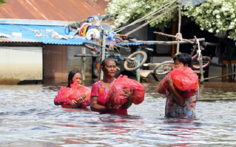 Sejumlah warga korban banjir membawa bungkusan sembako saat melintasi permukiman di tepian Sungai Kapuas, Sintang, Kalimantan Barat, Kamis (18/11/2021)./Antara