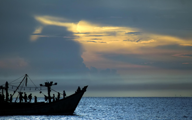 Kapal nelayan melintas dengan latar belakang matahari terbit di perairan Selat Malaka, Lhokseumawe, Aceh, Rabu (8/4/2020). -Antara