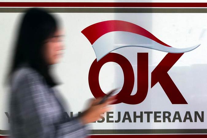Karyawan melintas di dekat logo Otoritas Jasa Keuangan (OJK) di Jakarta, Senin (13/5/2019)./Bisnis-Abdullah Azzam