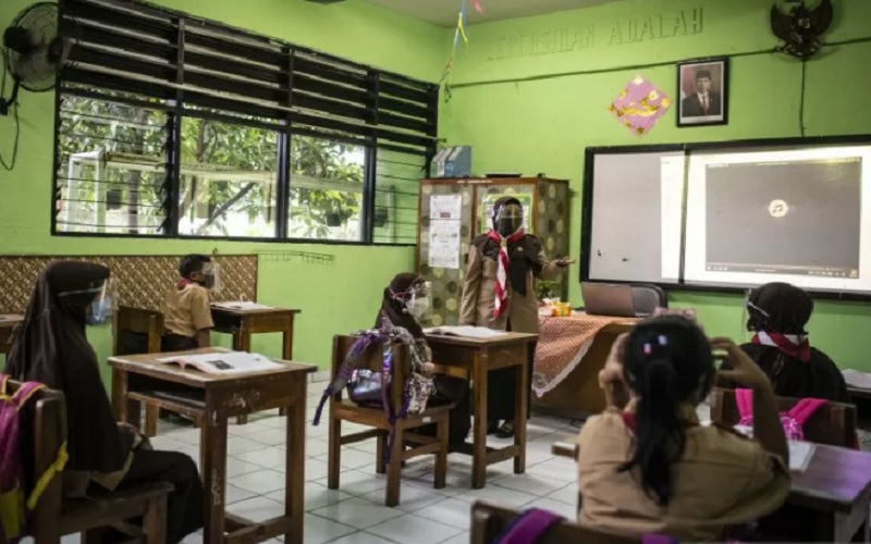 Guru (tengah) memberikan materi pelajaran kepada murid saat uji coba pembelajaran tatap muka pada hari pertama di SD Negeri Kenari 08 Pagi, Jakarta, Rabu (7/4/2021)./Antara