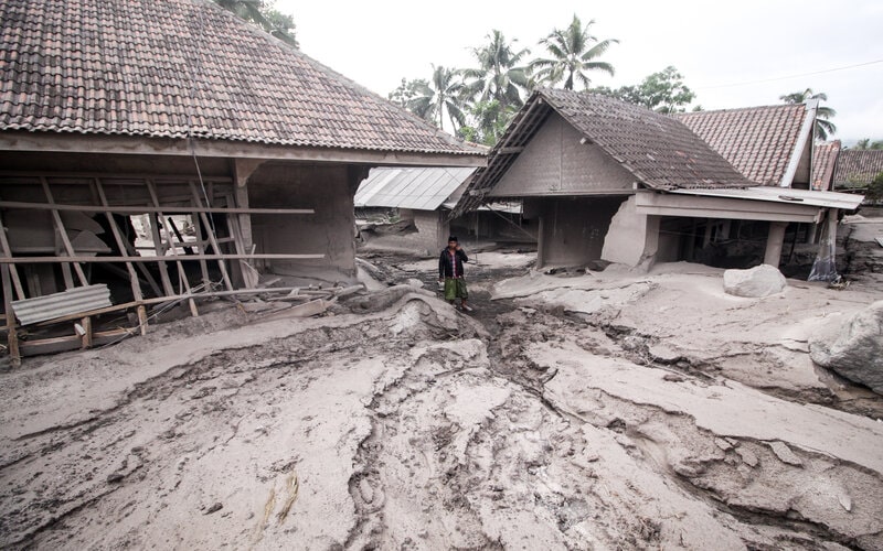 Warga melintas di rumah yang rusak akibat abu vulkanik letusan Gunung Semeru di Desa Sumber Wuluh, Lumajang, Jawa Timur, Minggu (5/12/2021). Akibat letusan Gunung Semeru tersebut sedikitnya puluhan rumah rusak./Antara-Umarul Faruq.