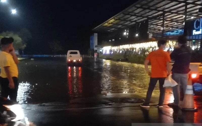 Sejumlah masyarakat mulai menyaksikan saat air laut mulai naik hingga menyebabkan banjir rob ke kawasan bisnis Kota Manado, Selasa (8/12/2021) malam./Antara-Nancy Tigauw.