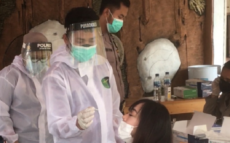 Seorang petugas memasukkan alat tes cepat (rapid test) antigen ke dalam hidung peserta rapid test antigen di Polsek Kelapa Gading, Jakarta Utara./Antara