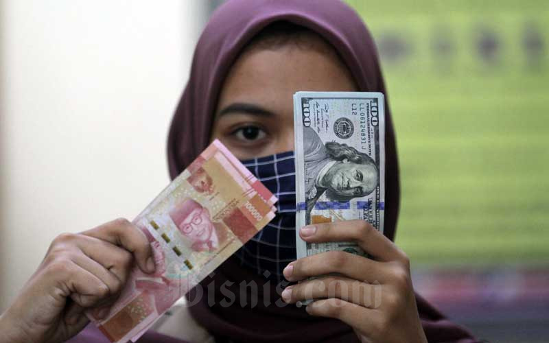 Karyawati menunjukan uang Rupiah dan dolar AS di salah satu gerai penukaran mata uang asing di Jakarta, Minggu (7/6/2020). Bisnis/Arief Hermawan P