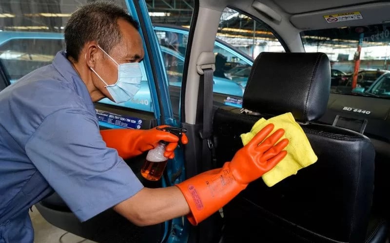 Ilustrasi pengemudi tengah membersihkan kabin mobil Bluebird. /Bluebird-Antara