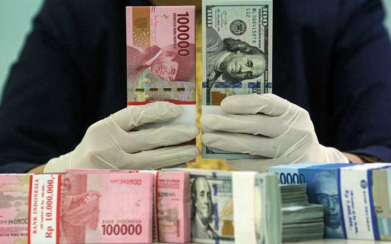 Karyawati salah satu bank memperlihatkan uang rupiah dan dolar di Jakarta, Kamis (29/4/2021). Bisnis/Arief Hermawan P