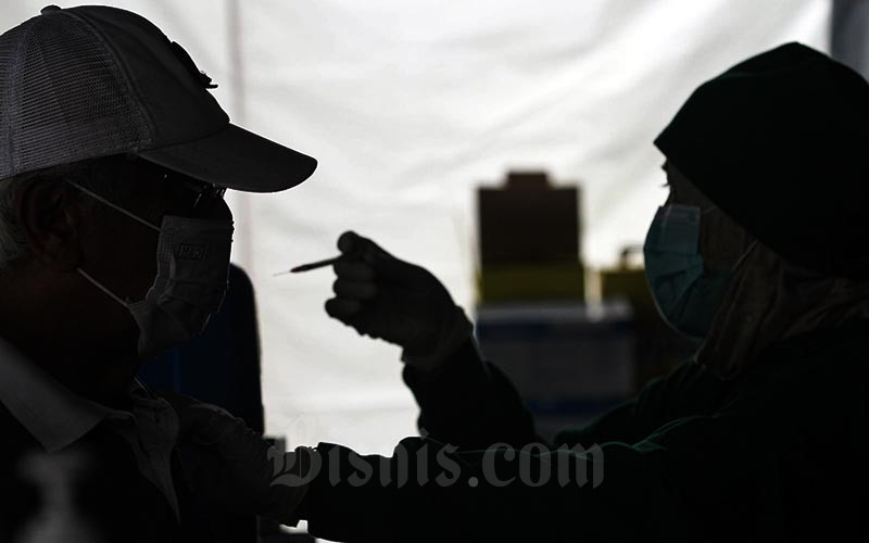 Tenaga kesehatan menyuntikkan cairan vaksin dosis ketiga kepada warga lansia saat vaksinasi booster Covid-19 di Puskesmas Kecamatan Kramat Jati, Jakarta, Rabu (12/1/2021). Bisnis/Arief Hermawan P