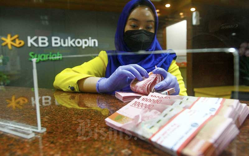 Karyawati menghitung uang rupiah di kantor cabang Bank KB Bukopin Syariah di Jakarta, Selasa (21/12/2021). Bisnis/Himawan L Nugraha