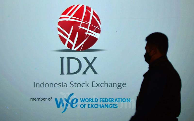 Karyawan melintas di dekat layar yang menampilkan logo Bursa Efek Indonesia (BEI) di Jakarta, Rabu (19/1/2022). Bisnis/Fanny Kusumawardhani 