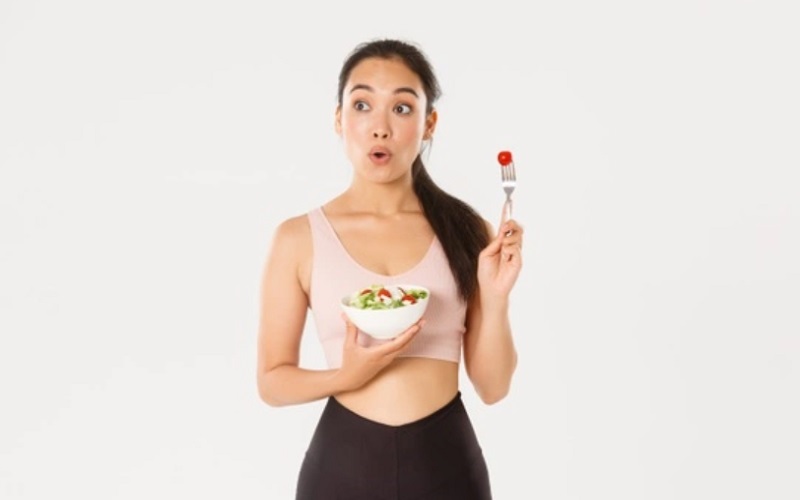 Ilustrasi perempuan mengonsumsi sayuran untuk mengurangi perut buncit/Freepik 