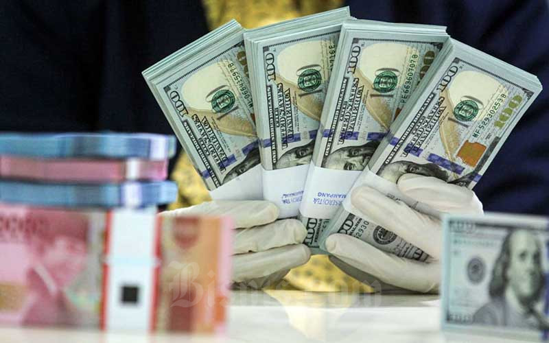 Karyawati salah satu bank memperlihatkan uang rupiah dan dolar di Jakarta, Kamis (29/4/2021). Bisnis/Arief Hermawan P